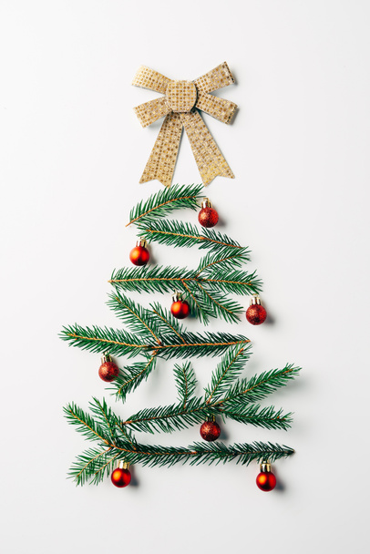 top view of green pine branch decorated as festive christmas tree with bow on white background - Photo, Image