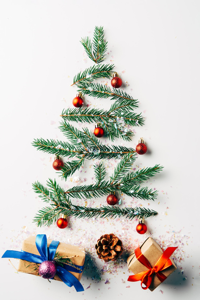 felülnézet zöld fenyő ág díszített ünnepi karácsonyi fa ajándékok és csillog fehér háttér - Fotó, kép
