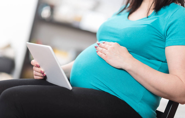 Kobieta w ciąży za pomocą cyfrowego tabletu w domu - Zdjęcie, obraz