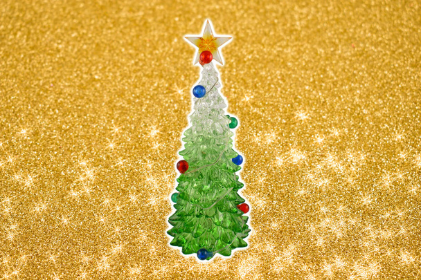 Golden christmas background with a tree stock images. Simple Christmas card. Christmas decoration on a golden background. Christmas tree with a star. Holiday background with copy space for text - Photo, Image