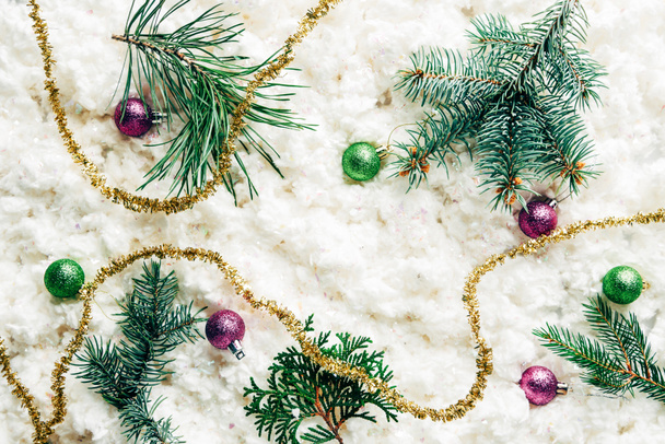lapos feküdt fenyő fa ágai, karácsonyi játékok, ünnepi koszorú fehér vattát háttér - Fotó, kép