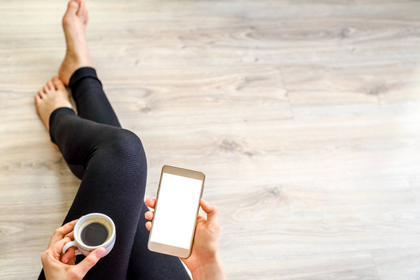 Moderní žena se smartphonem v ruce a relaxaci u kávy pomocí mobilního telefonu s bílým plátnem. Podnikatelka pracující doma nebo online nakupování koncept. - Fotografie, Obrázek