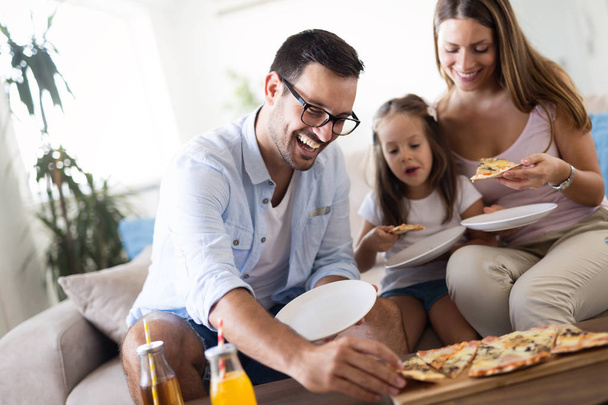 Retrato de família feliz compartilhando pizza juntos em casa
 - Foto, Imagem