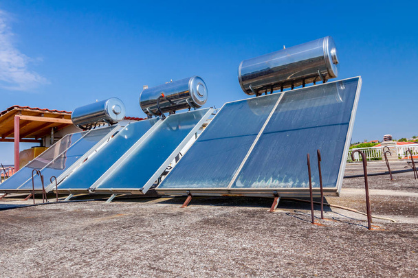 A megújuló napenergia felhasználására szolgáló vízpaneleket háztetőre, napenergiával működő melegvíz-rendszerbe helyezik. Modern energiatakarékossági technológia - Fotó, kép