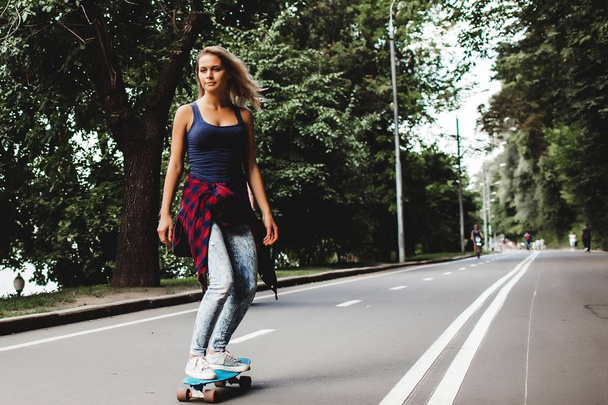 blonde teenager girl riding skateboard on road  - Foto, Imagem