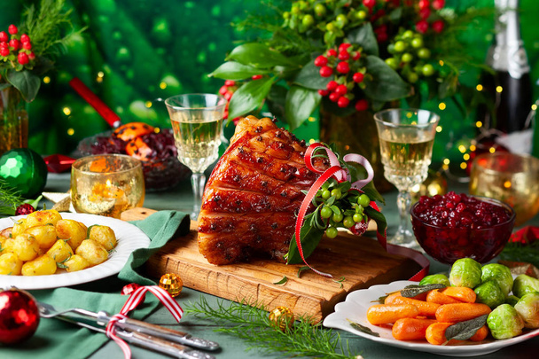 Glazed roast ham with cloves,sparkling wine and traditional vegetables dishes for Christmas dinner. - 写真・画像