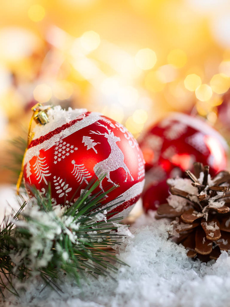 Bolas rojas de Navidad con decoración y ramas de abeto con cono de pino sobre fondo dorado brillante
 - Foto, imagen