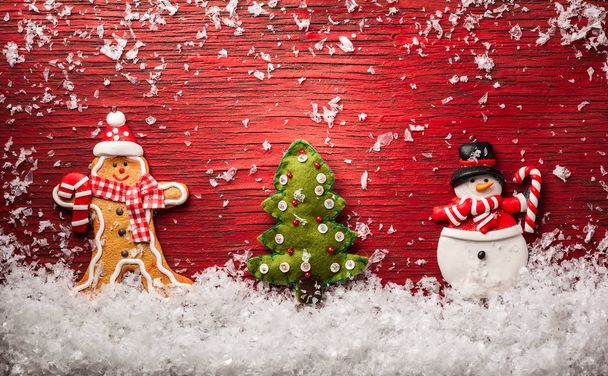 Christmas concept with snowman,gingerbread man and christmas tree on a red wooden background - Foto, Bild
