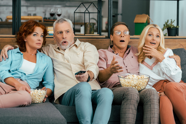 shocked mature friends sitting on couch and watching tv together - Foto, Bild