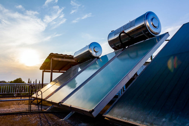 Οι πίνακες νερού για τη χρήση ανανεώσιμων πηγών ηλιακής ενέργειας τοποθετούνται στην οροφή του σπιτιού, ηλιακό σύστημα ζεστού νερού. Σύγχρονη τεχνολογία εξοικονόμησης ενέργειας - Φωτογραφία, εικόνα