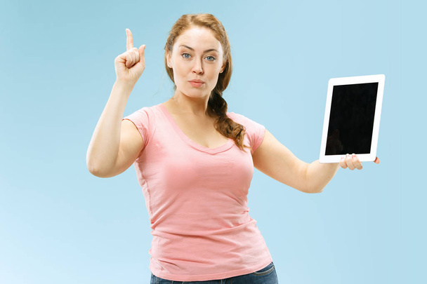 Portrait of a confident casual girl showing blank screen of laptop isolated over blue background - Foto, Imagem