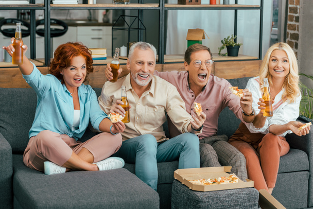excited mature friends drinking beer and eating pizza at home - Fotoğraf, Görsel