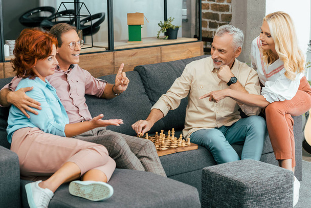 Homem feliz jogando xadrez com amigos multiétnicas em casa na sala