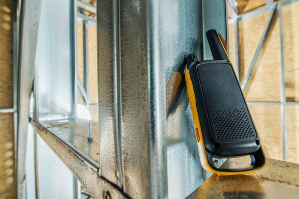 Walkie Talkie Communication in the Construction Site. Yellow Device on the Metal Framing. - Photo, Image