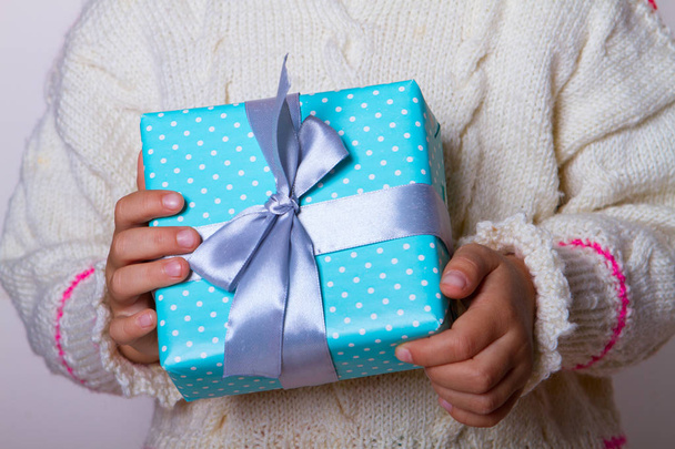 caixa de presente azul bolinhas nas mãos da criança
 - Foto, Imagem
