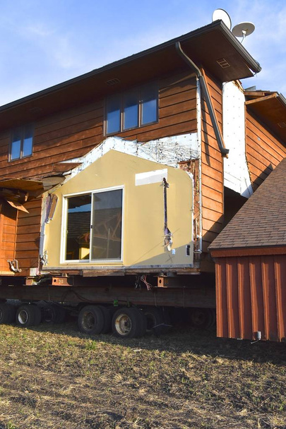 ein Haus, das in Abschnitte aufgeteilt ist, wird bewegt und ruht auf langen Stahlträgern - Foto, Bild