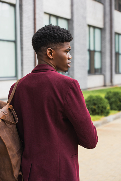 красивый молодой студент с кожаным рюкзаком, идущий по улице
 - Фото, изображение