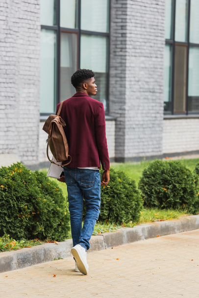 vista trasera de un joven estudiante con mochila y cuadernos caminando por la calle
 - Foto, Imagen