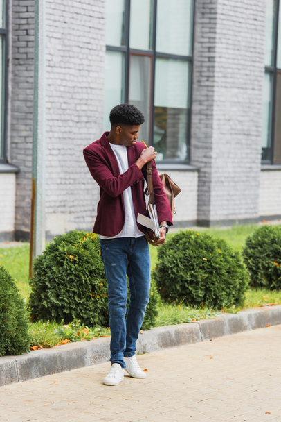 stylish young student with backpack and notebooks standing on street - Photo, Image