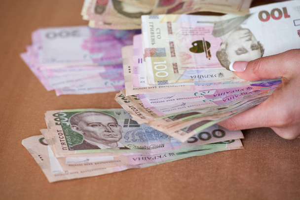 Χέρια που κρατούν Γρίβνα Ουκρανίας χρήματα. Ένα πακέτο των ουκρανικών χρήματα στα χέρια των γυναικών. - Φωτογραφία, εικόνα
