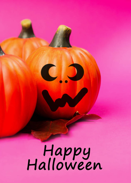 Halloween holiday background. Halloween pumpkin jack o lantern decor with funny faces on pink background. Text happy halloween. - Фото, изображение