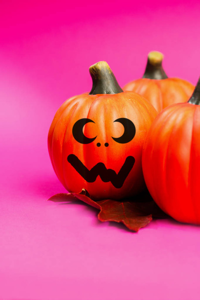 Tło wakacje Halloween. Halloween pumpkin jack o lantern wystrój z śmieszne twarze na różowym tle. Kopiować miejsca na tekst. - Zdjęcie, obraz