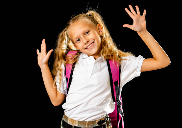 Adorable beautiful little schoolgirl with big pink schoolbag feeling excited and happy on a black background - Photo, Image