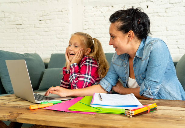 Mutter hilft jungen Mädchen bei Hausaufgaben mit Laptop und Schulbüchern zu Hause auf dem Sofa sitzend. Elternschaft, Hausaufgaben und Bildungskonzept - Foto, Bild