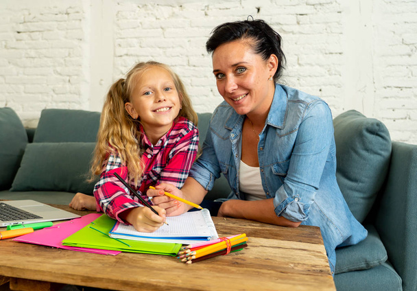 Beautiful mother helping her young blonde cute sweet girl doing homework at home. Homework parenting and education concept - Valokuva, kuva
