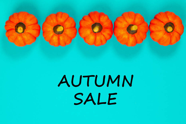Autumn sale background. Five orange pumpkins on blue background. View from above. Text Autumn sale. - Photo, Image