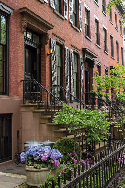Row of old brownstone buildings along an empty sidewalk block in the Greenwich Village neighborhood of Manhattan, New York City NYC - 写真・画像