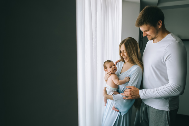 selective focus of happy family carrying little baby boy in front of curtains at home - Zdjęcie, obraz