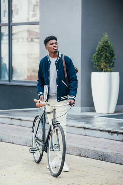 handsome african american freelancer with documents and bike  - Photo, Image