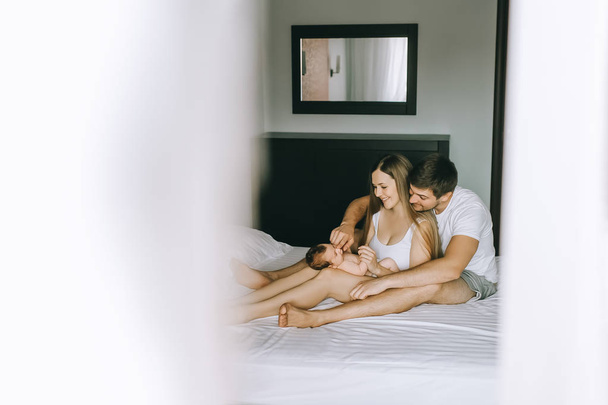 selective focus of happy family playing with infant son in bed at home - Φωτογραφία, εικόνα