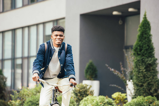 african american smiling man riding bicycle in city - Foto, Imagem