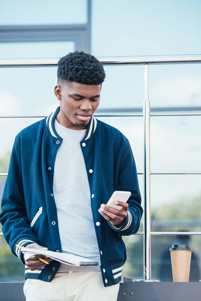 handsome african american freelancer with documents using smartphone in city - Foto, Bild