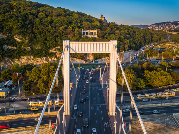 Budapest, Hungría - Vista aérea del puente Elisabeth (Erzsebet escondido) y la colina Gellert al amanecer con tráfico pesado y tranvías amarillos tradicionales
 - Foto, Imagen
