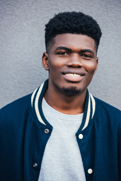 portrait of smiling african american man in trendy blue bomber  - Photo, image