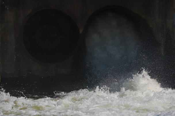 Agua liberada de la presa a través de tuberías en el canal
. - Foto, Imagen