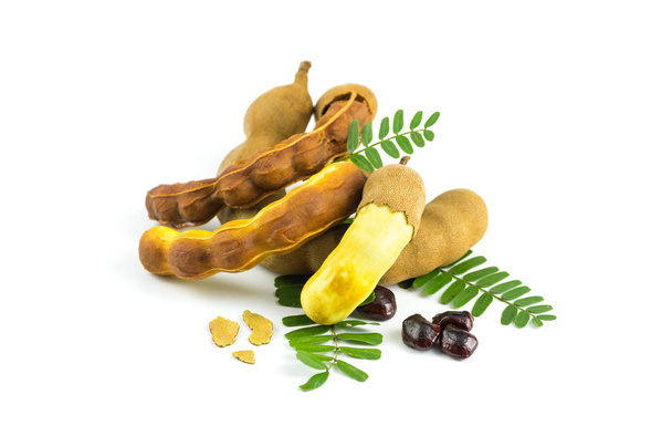 Свежий сладкий тамаринд изолирован на белом фоне с листьями, семенами и корой тамаринда, может быть использован в качестве напитка для здоровья, тамаринд сок
. - Фото, изображение
