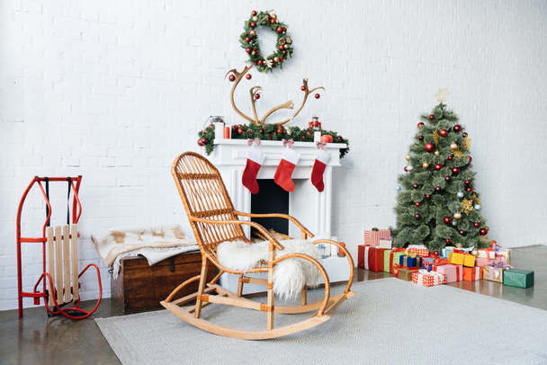 habitación decorada con mecedora, árbol de Navidad y regalos para la celebración de las vacaciones de invierno
 - Foto, Imagen