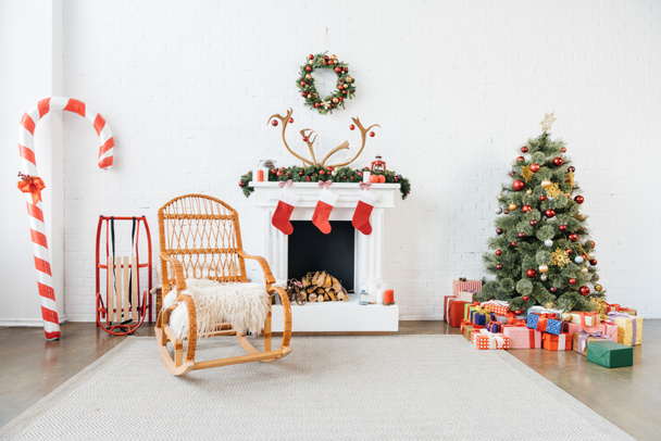 διακοσμημένο δωμάτιο με λικνίζοντας καρέκλα, χριστουγεννιάτικο δέντρο και τα δώρα για γιορτή χειμερινές διακοπές - Φωτογραφία, εικόνα