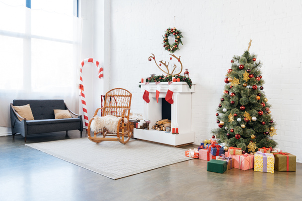 habitación decorada con mecedora, árbol de Navidad y regalos para la celebración de las vacaciones de invierno
 - Foto, Imagen