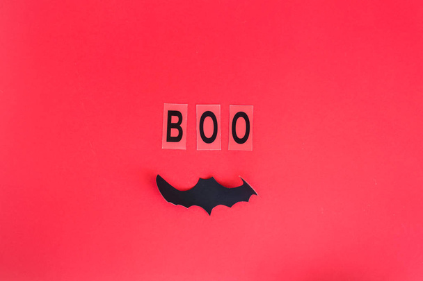 Boo napisał w czarne litery obok bat na czerwonym tle. Koncepcja dekoracji Halloween. Widok z góry, płaskie leżał, miejsce - Zdjęcie, obraz