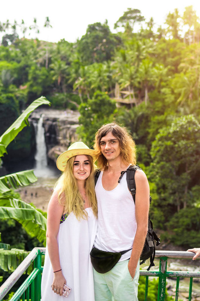Pareja joven de luna de miel en la selva en el fondo de la cascada de agua. Isla de Bali
. - Foto, imagen
