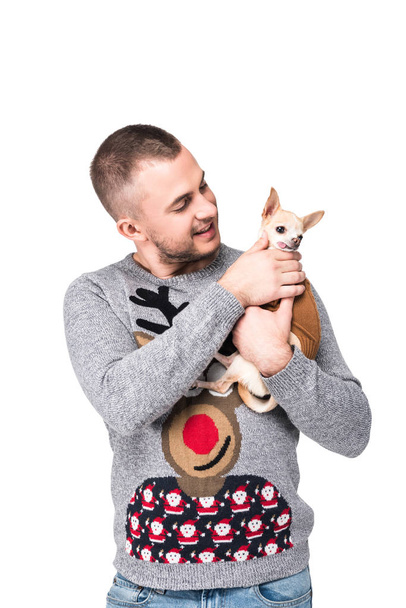 Porträt eines Mannes im festlichen Winterpullover mit kleinem Chihuahua-Hund auf weißem Hintergrund - Foto, Bild