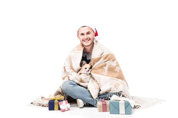happy man in santa claus hat with chihuahua dog and christmas gifts isolated on white - Fotó, kép