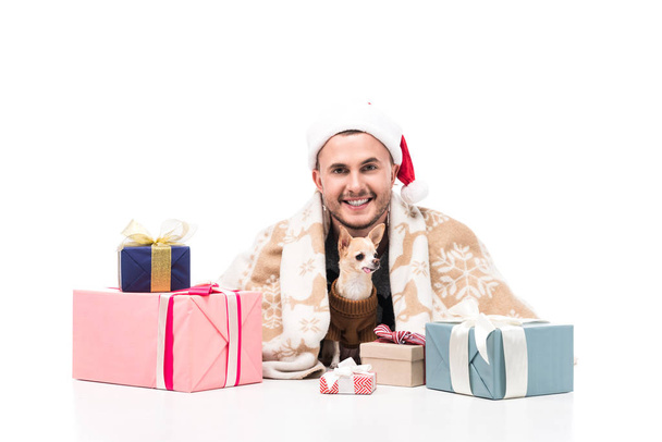 ευτυχισμένος άνθρωπος στον Αϊ Βασίλη καπέλο με Τσιουάουα σκυλί και χριστουγεννιάτικα δώρα απομονωθεί σε λευκό - Φωτογραφία, εικόνα