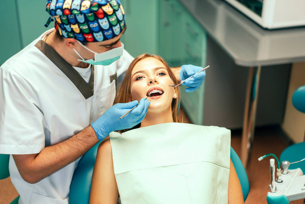 Dentist examine female patient with braces in denal office - Foto, Bild