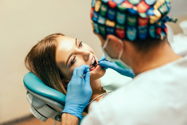 Dentist examine female patient with braces in denal office - Zdjęcie, obraz